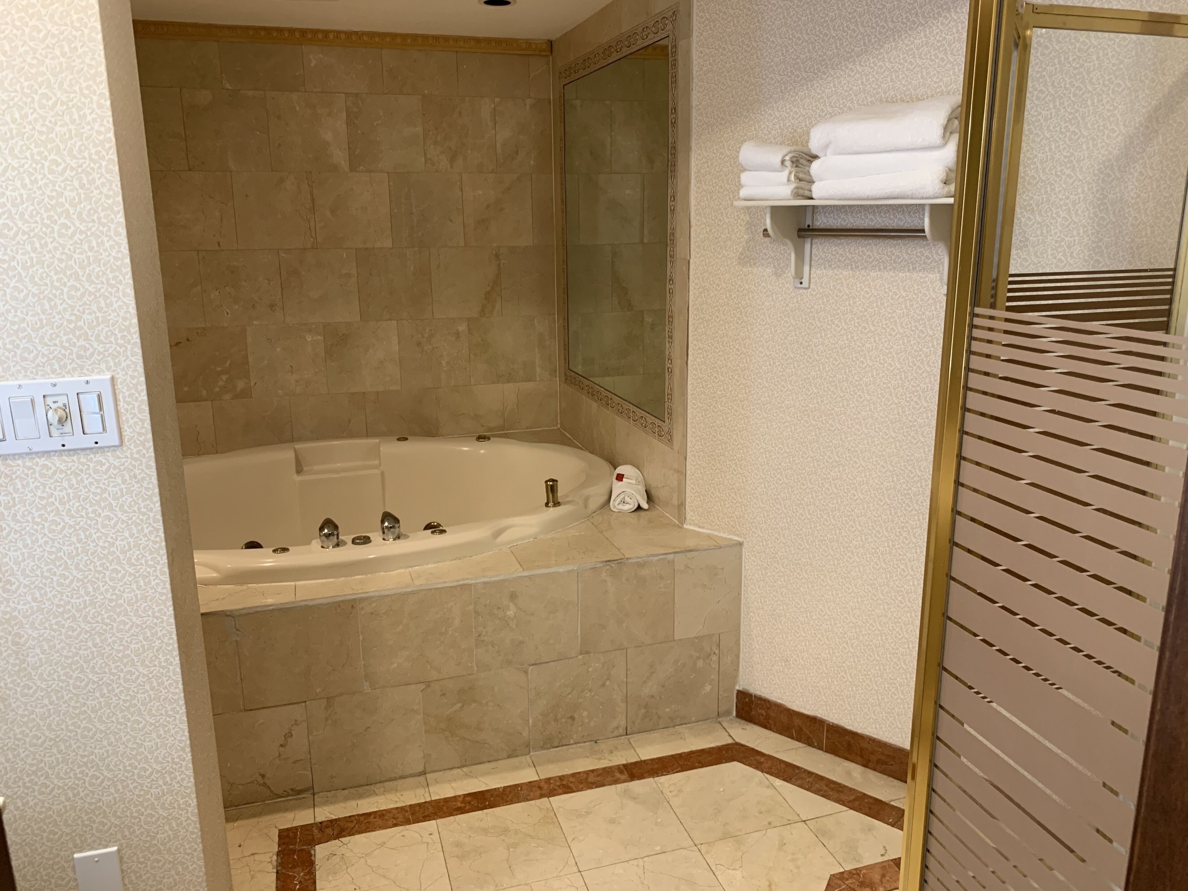 A bathroom with a large bathtub, a mirror, and a towel rack.