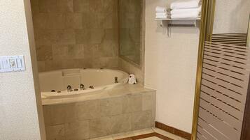 A bathroom with a large bathtub, a mirror, and a towel rack.