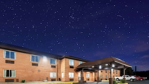 A brick building with a covered parking area and a truck parked outside. - Super 8 by Wyndham Fairmont (Fairmont)