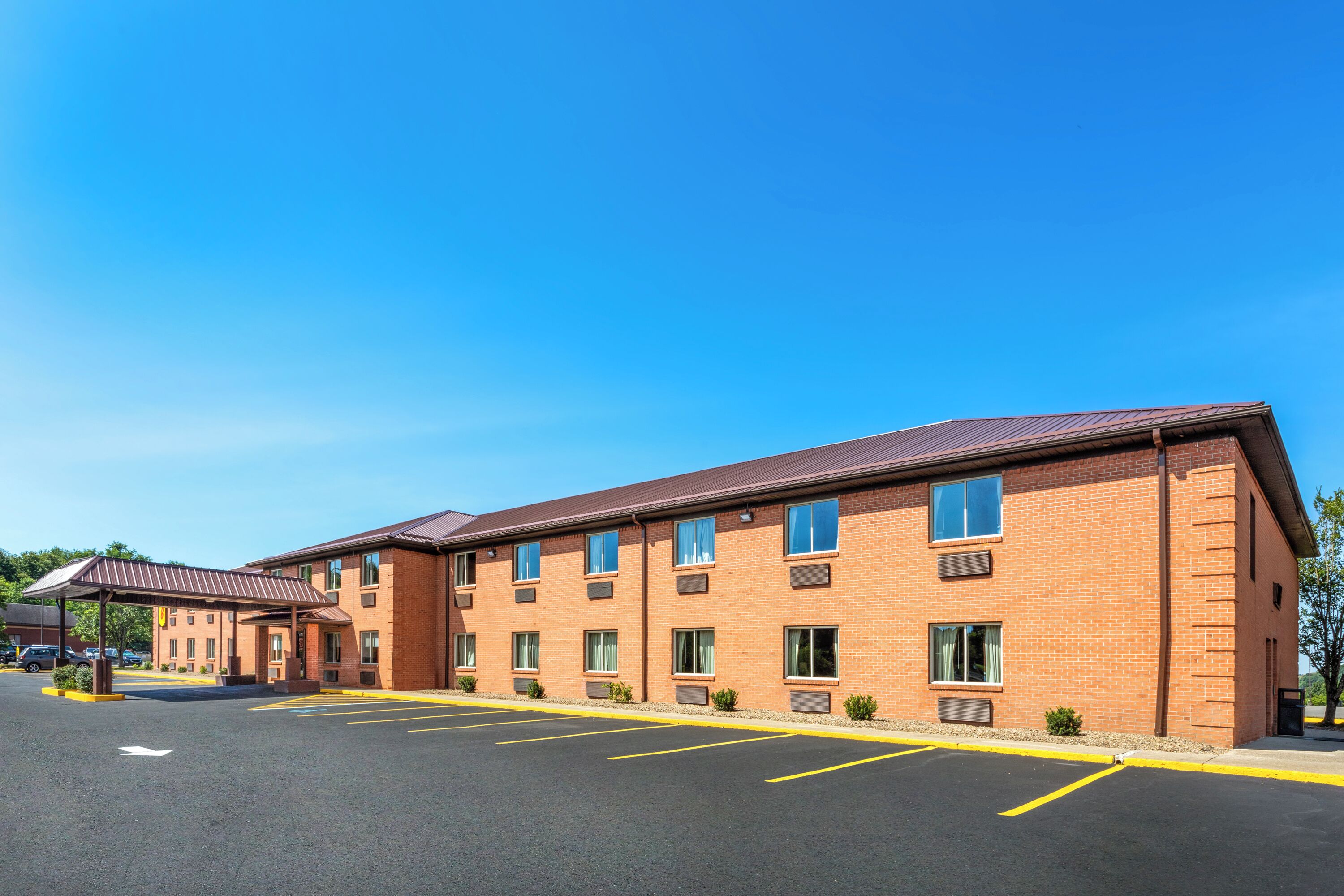 Un immeuble de plusieurs étages, construit en briques, avec un espace de stationnement couvert et un ciel d’un bleu éclatant.