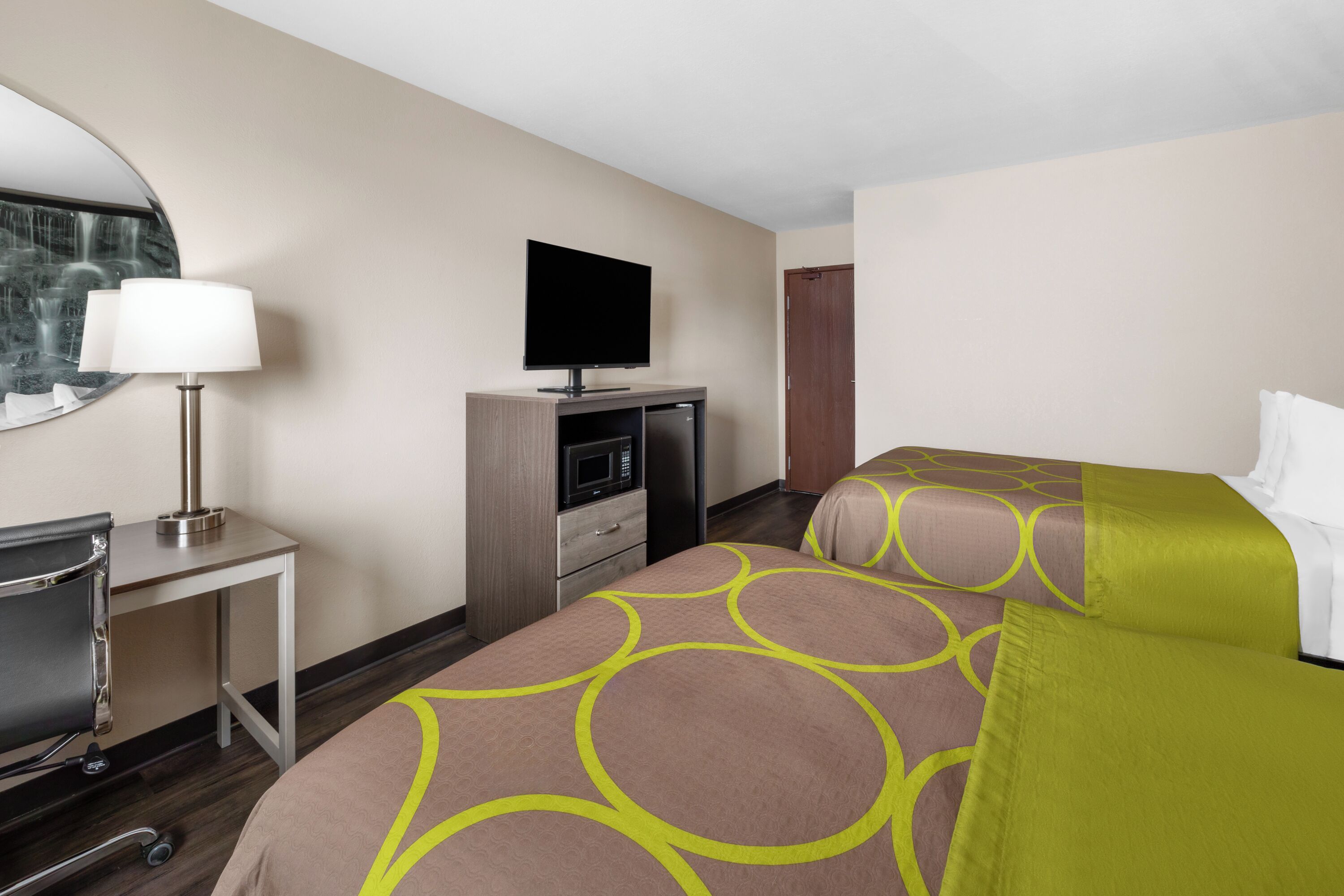 A hotel room with a bed, a desk with a lamp, a television, and a microwave.