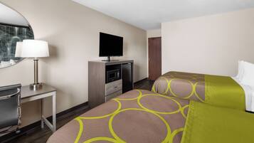 Quarto de hotel com uma cama, uma mesa com luminária, televisão e micro-ondas.