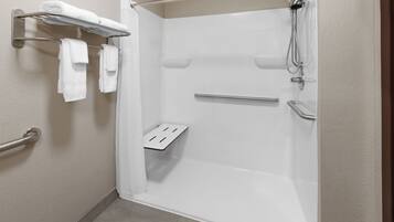 Une salle de bain moderne dotée d’une douche à l’italienne, de barres d’appui et d’un porte-serviettes.