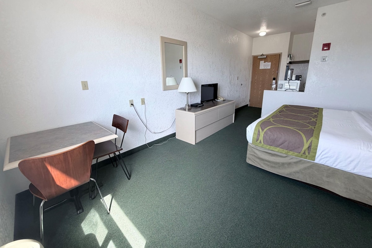 Une chambre d’hôtel comprenant un lit, un bureau avec une chaise, une télévision et un miroir.
