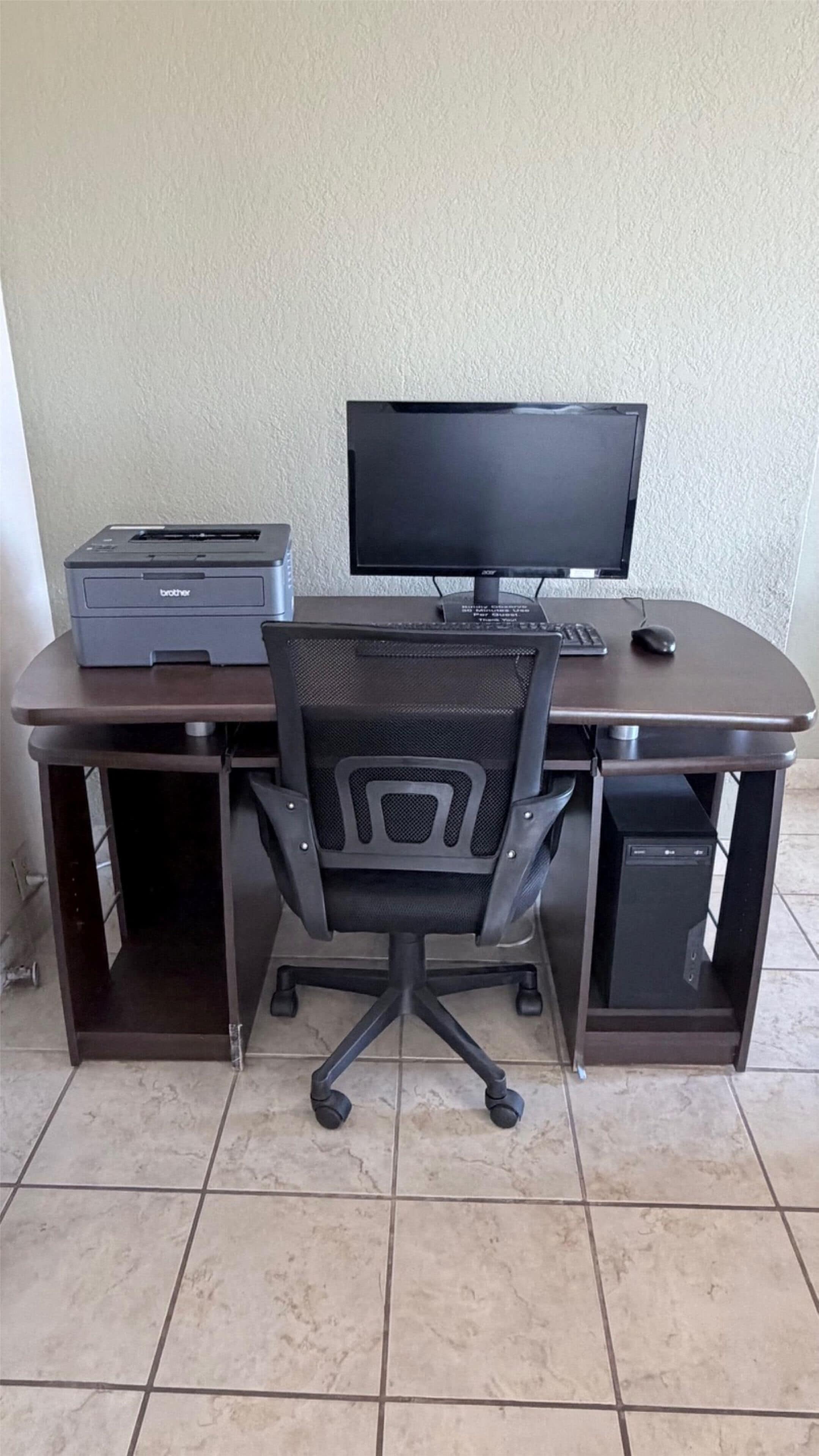 Un escritorio con una computadora, una impresora y una silla.