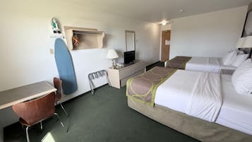 A hotel room with a desk, chair, two beds, a TV, and a surfboard.