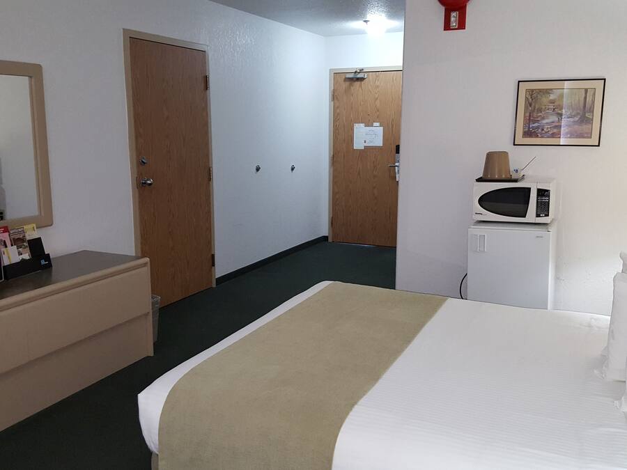 Habitación de hotel con cama, televisión, microondas, cómoda y puerta.