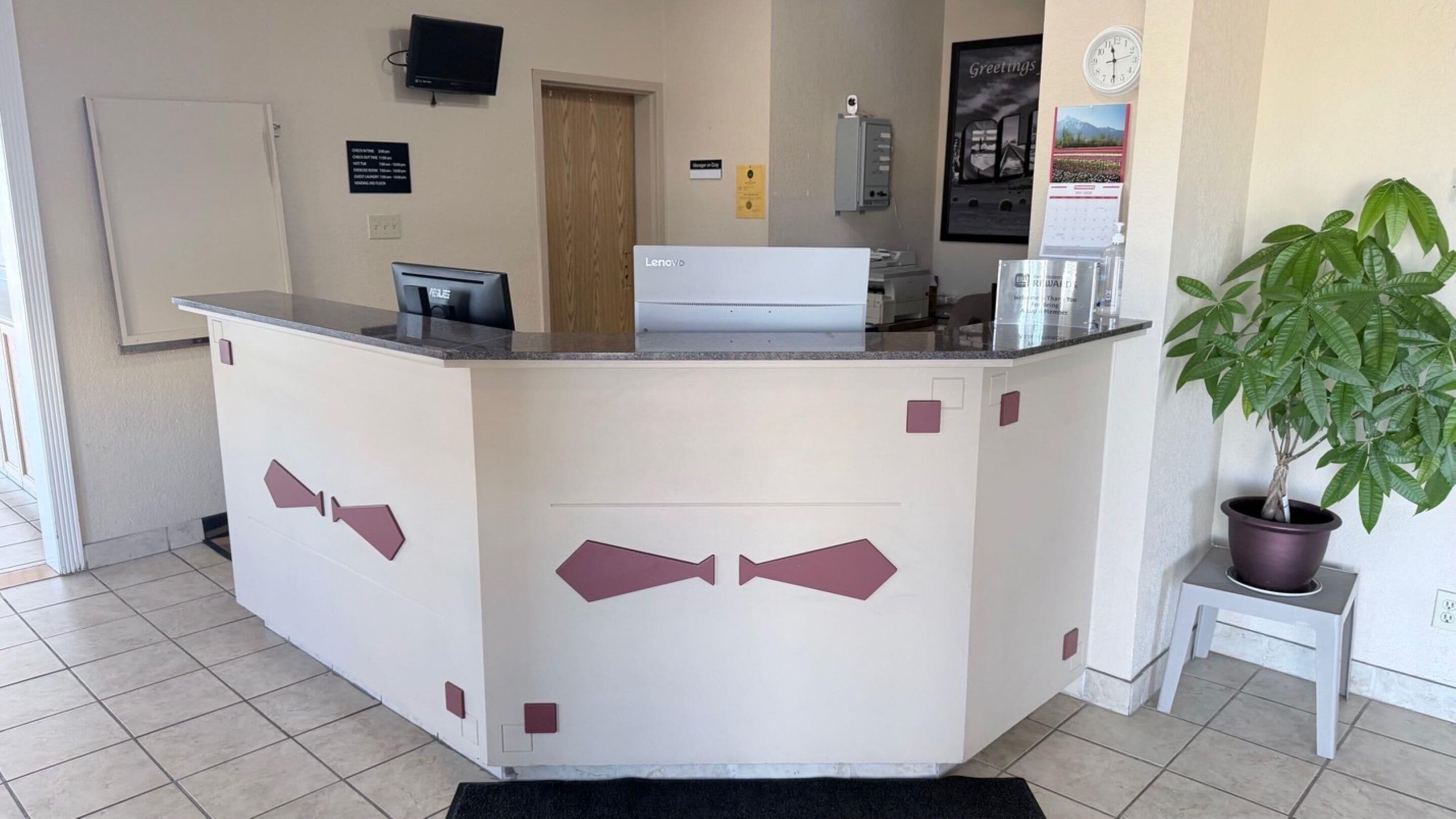 A reception desk with a flat-screen TV, a clock, and a calendar.