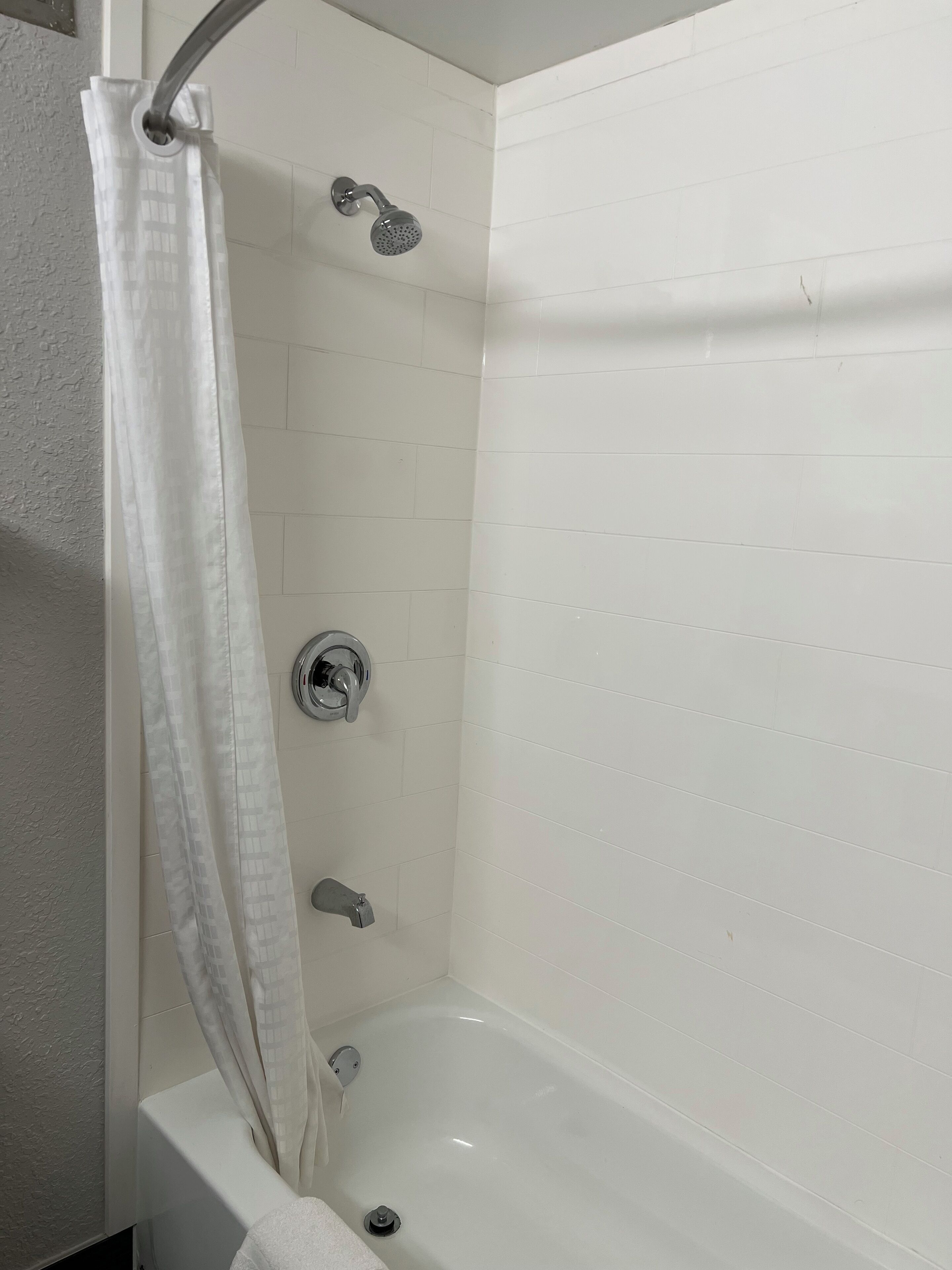 Un baño con bañera, cabezal de ducha y cortina.