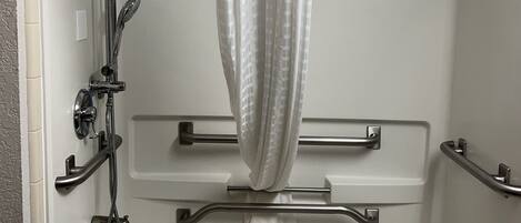 Un espace douche équipé d’un pommeau de douche à main, d’une barre d’appui et d’un porte-serviettes.