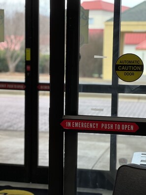 A door with an emergency push to open sign and an automatic caution door sign. - Super 8 by Wyndham Clemmons/Bermuda Run/Winston-Salem I-40 (Clemmons)