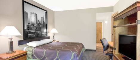 Una habitación de hotel con una cama, dos lámparas de noche, un televisor y un escritorio con una silla.