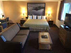 A hotel room with a bed, a sofa, a TV, and a desk.