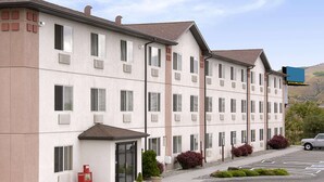 Un hôtel à plusieurs étages, doté d’une façade sobre, de grandes fenêtres et d’un parking.