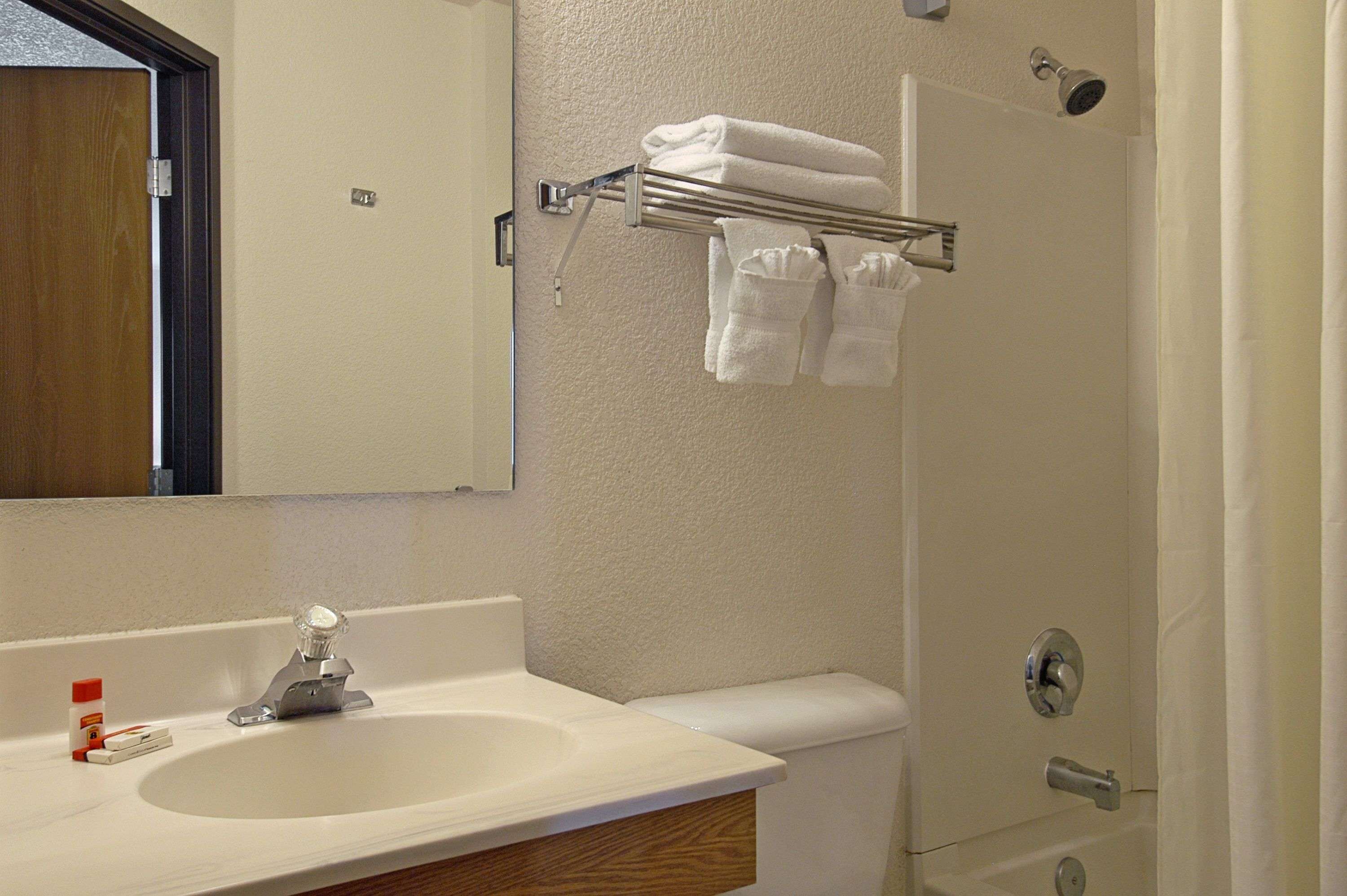 Un baño con lavamanos, espejo, toallero y retrete.