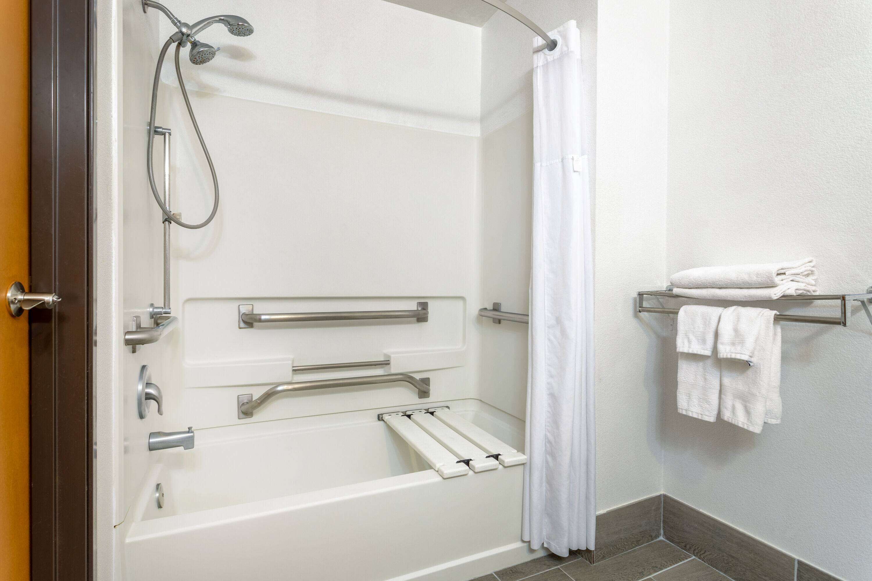 A walk-in shower with grab bars, a towel rack, and a shower curtain.