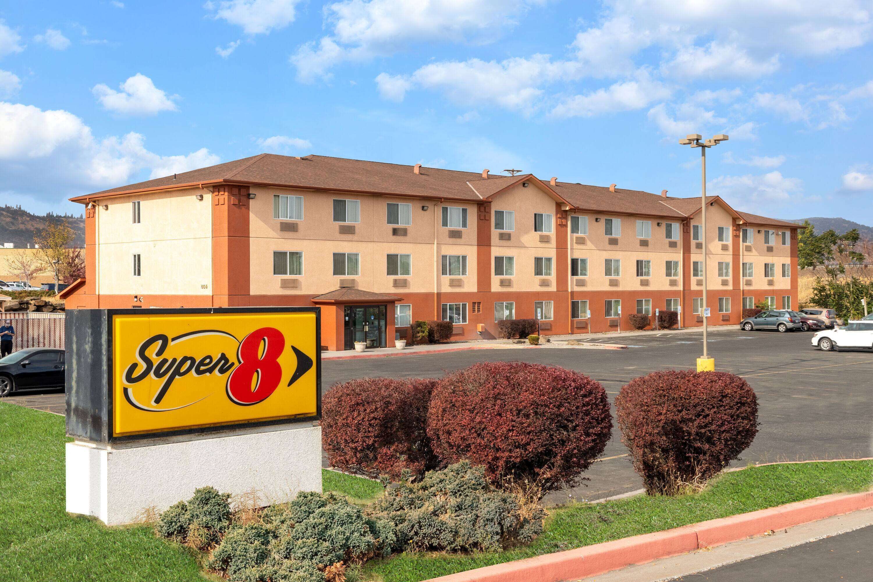 A Super 8 hotel with a large sign, multiple windows, and a parking lot.
