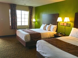 Habitación de hotel con dos camas, una pared verde y dos lámparas de noche.