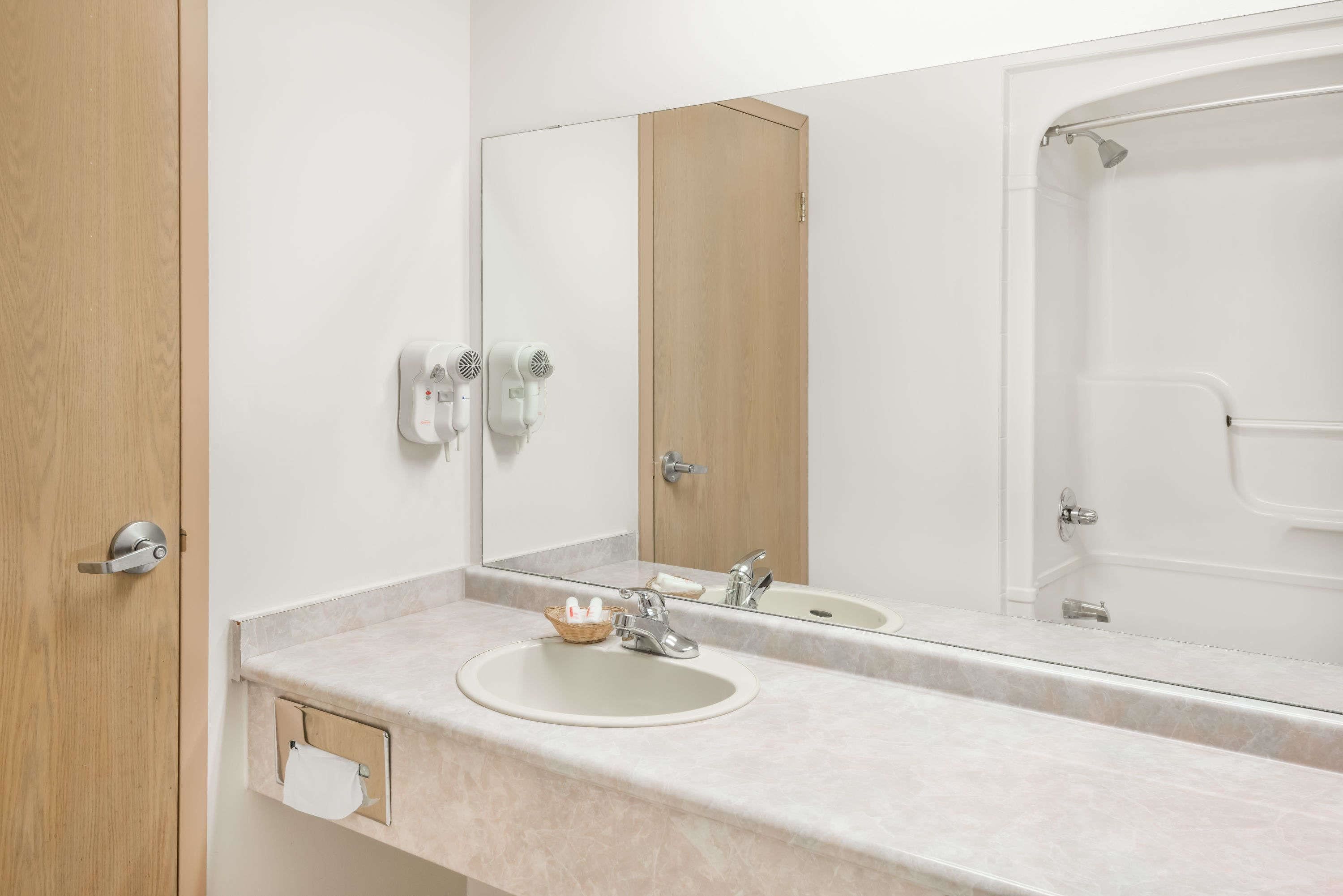 A bathroom with a sink, mirror, and shower.