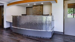 Zona de recepción con un pilar de piedra, mostrador con azulejos y viga de techo de madera.