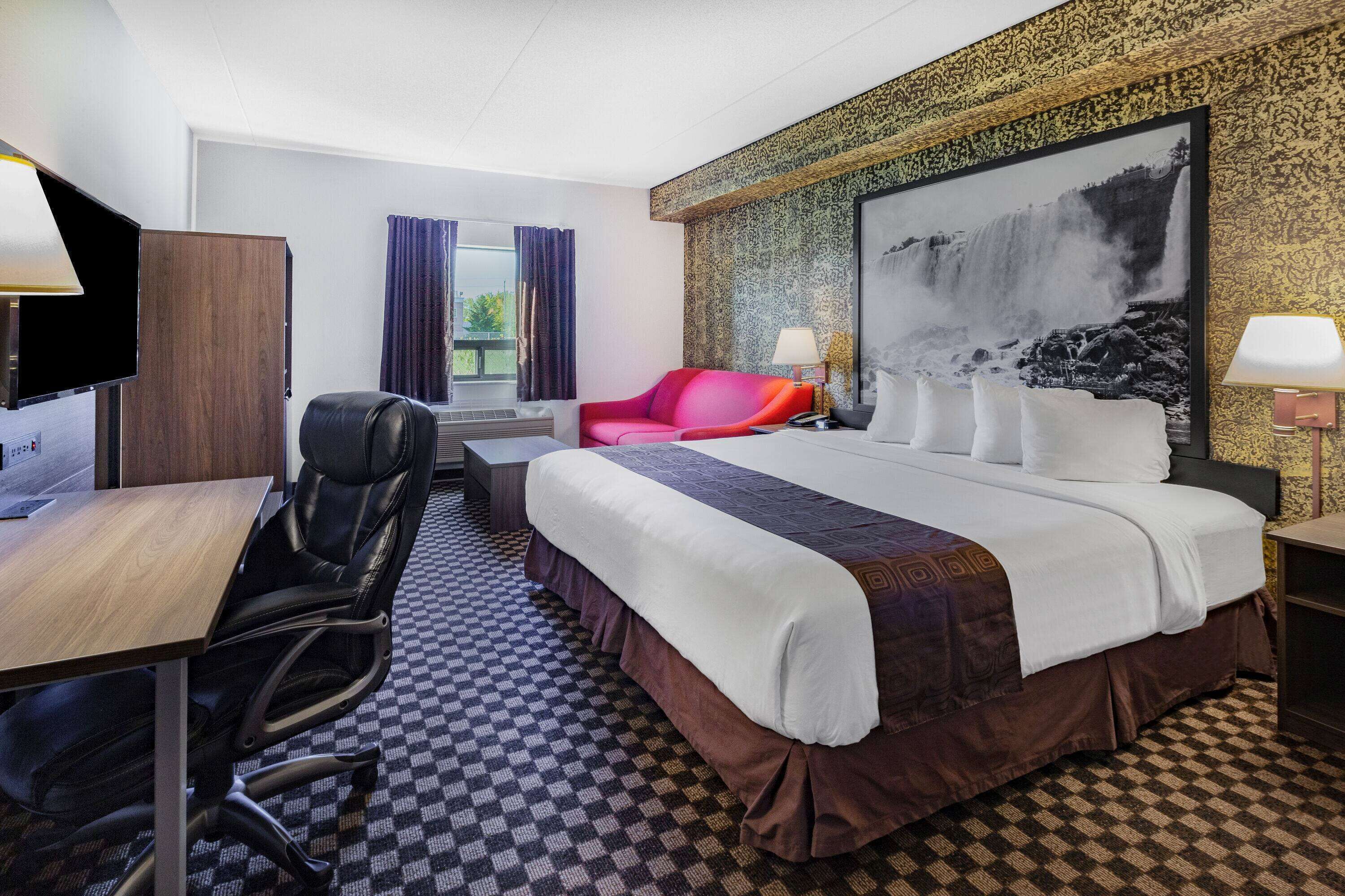 Une chambre d’hôtel avec un grand lit, un bureau avec une chaise, une télévision et une fenêtre avec des rideaux.