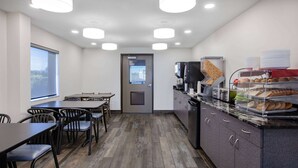 Una cocina moderna con comedor, equipada con cafetera, microondas y una exhibición de pan.