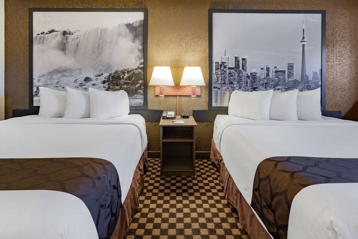 Une chambre d’hôtel avec deux lits, un sol à carreaux, une table de chevet avec des lampes et deux grandes images encadrées au mur.