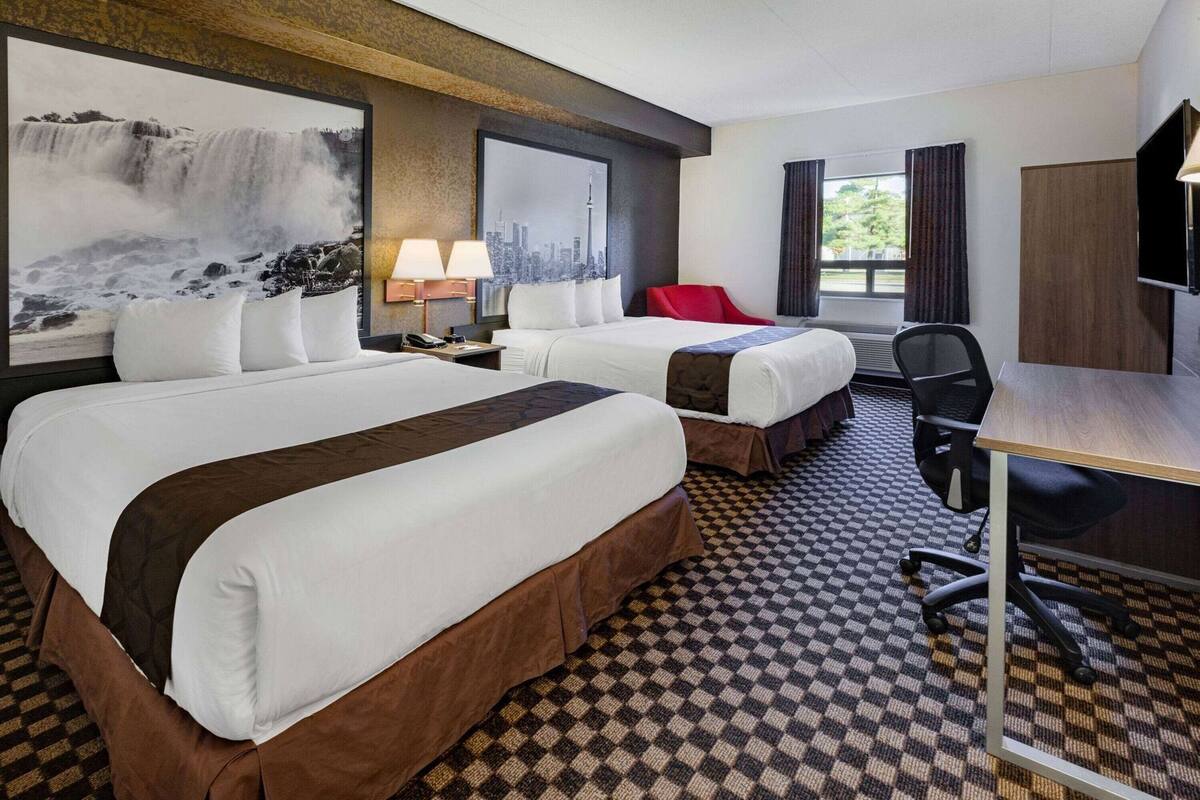 Une chambre d’hôtel avec deux lits, un bureau, une chaise et une télévision.