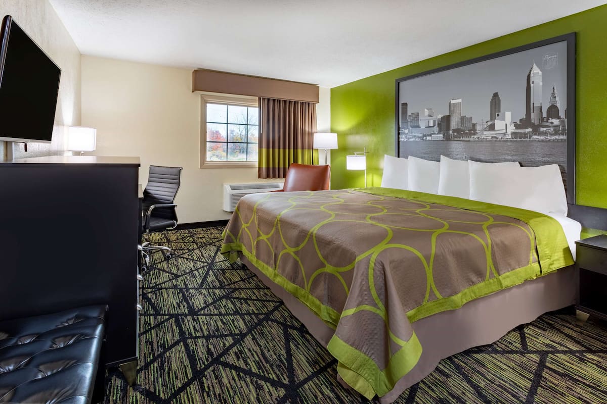 Ein Hotelzimmer mit Bett, Schreibtisch, Sessel, Fernseher und Stadtbild.