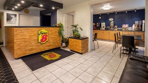 Un espace d’accueil avec un comptoir en bois, une horloge et un coin café.