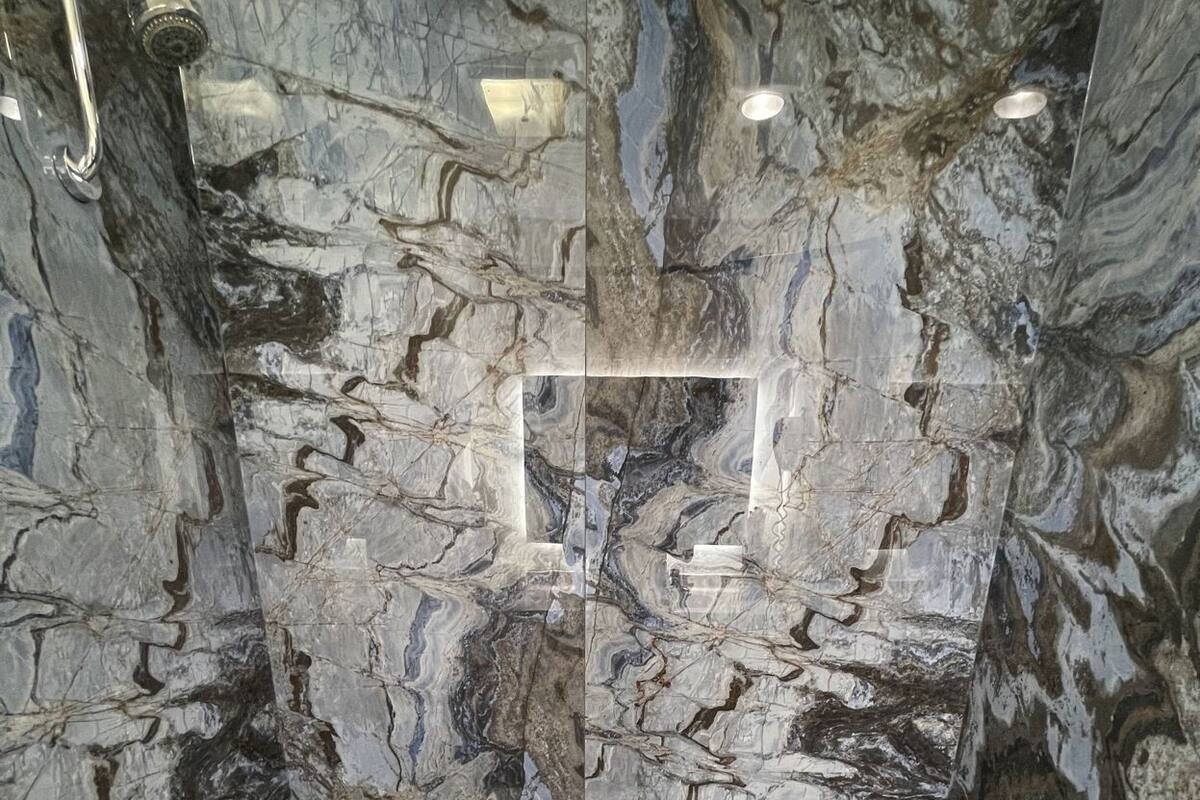 Ein Badezimmer mit Marmorwand, einer Badewanne und einer Toilette.