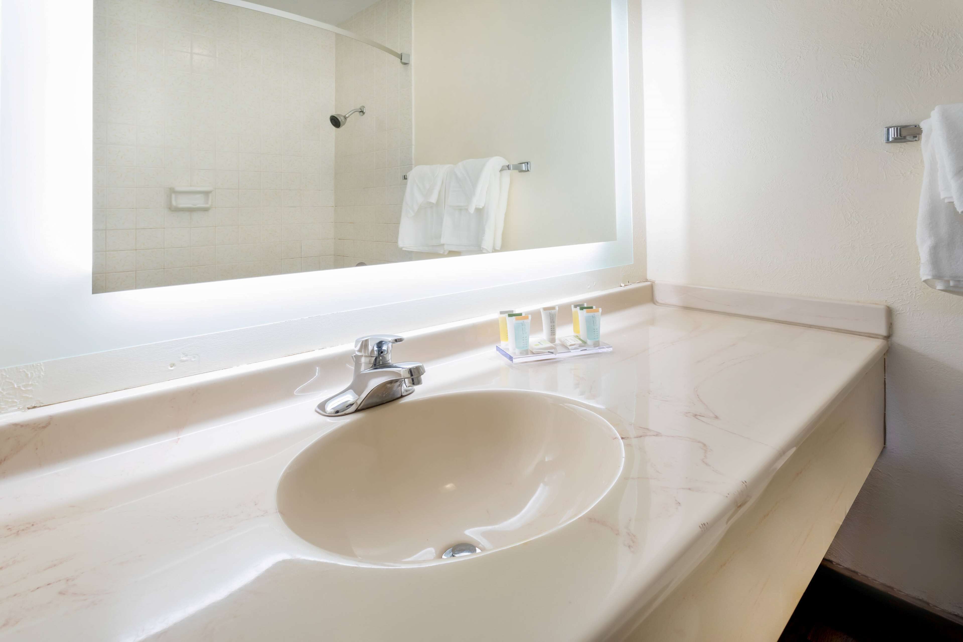 A bathroom with a white sink, a mirror, and a shower area.