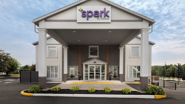 A hotel entrance with a sign reading "spark by Hilton," featuring a modern design with a covered entrance and a landscaped area in front. - Spark By Hilton Woodstock (Woodstock)