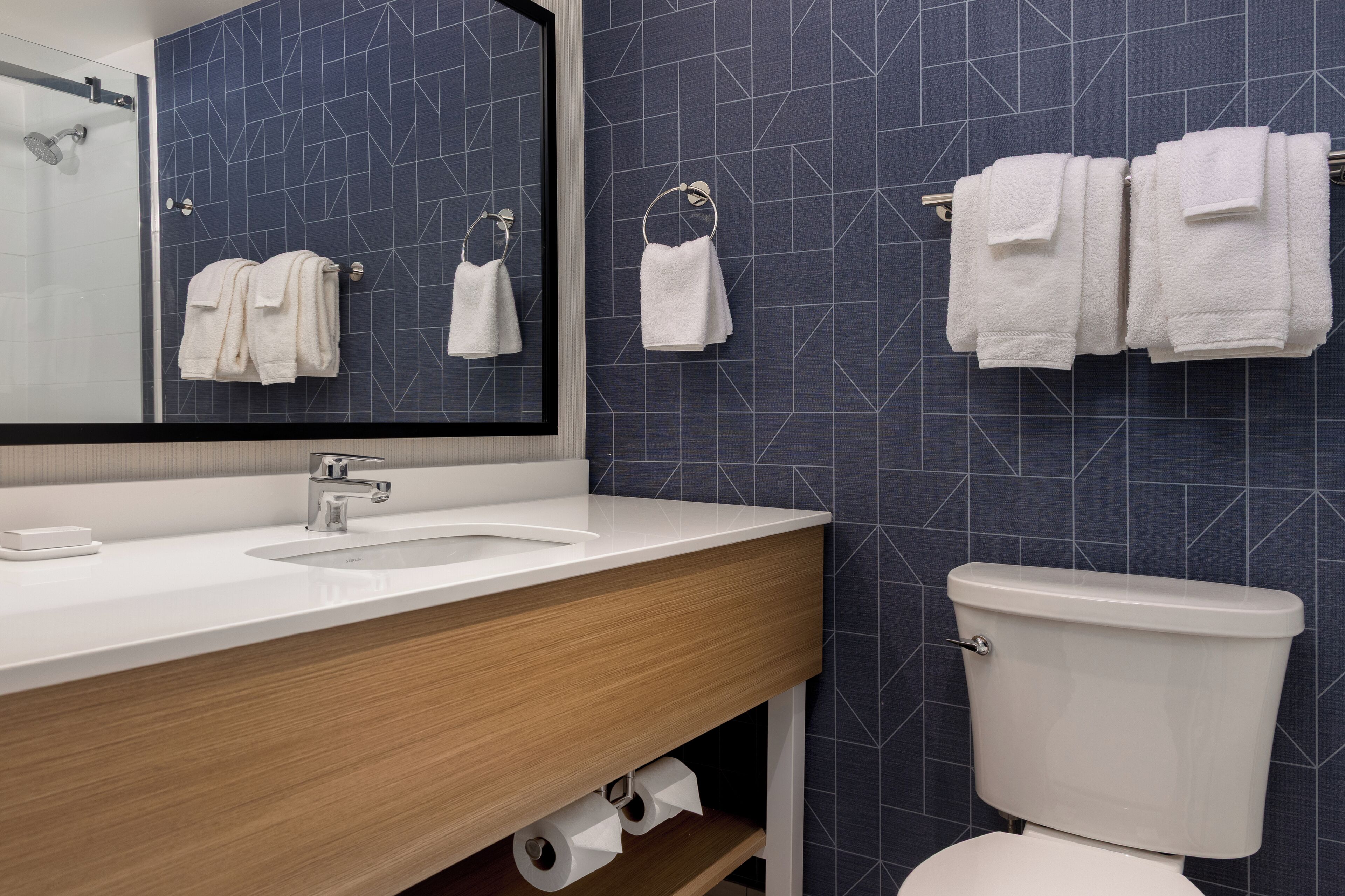 A modern bathroom with a white sink, a mirror, and a toilet.