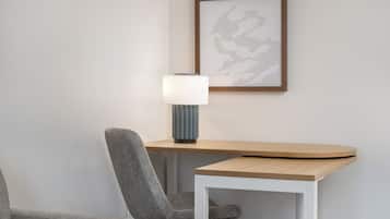 Une chambre moderne avec un bureau en bois, une chaise grise et une œuvre d’art encadrée accrochée au mur.