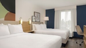 A hotel room with two beds, a desk, a chair, and a large window with curtains. - Spark By Hilton Woodstock (Woodstock)
