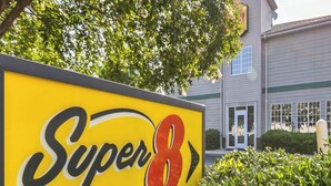 Señal de 'Super 8 by Wyndham' con un edificio al fondo.
