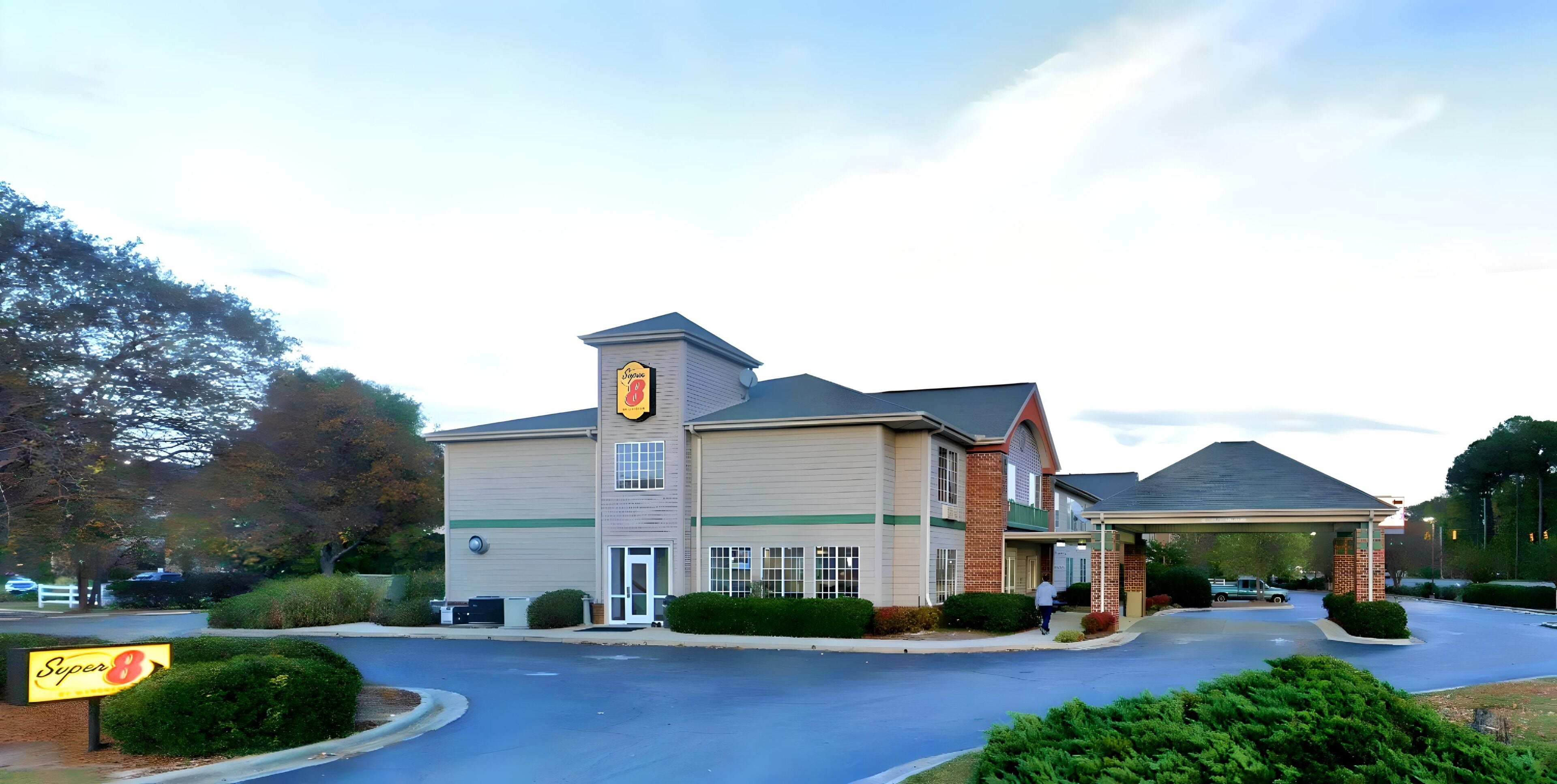 A Super 8 hotel with a two-story building, a covered parking area, and well-maintained landscaping.