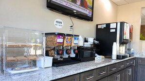 Una barra de desayuno equipada con una máquina de café, un refrigerador y un televisor que muestra un noticiero.