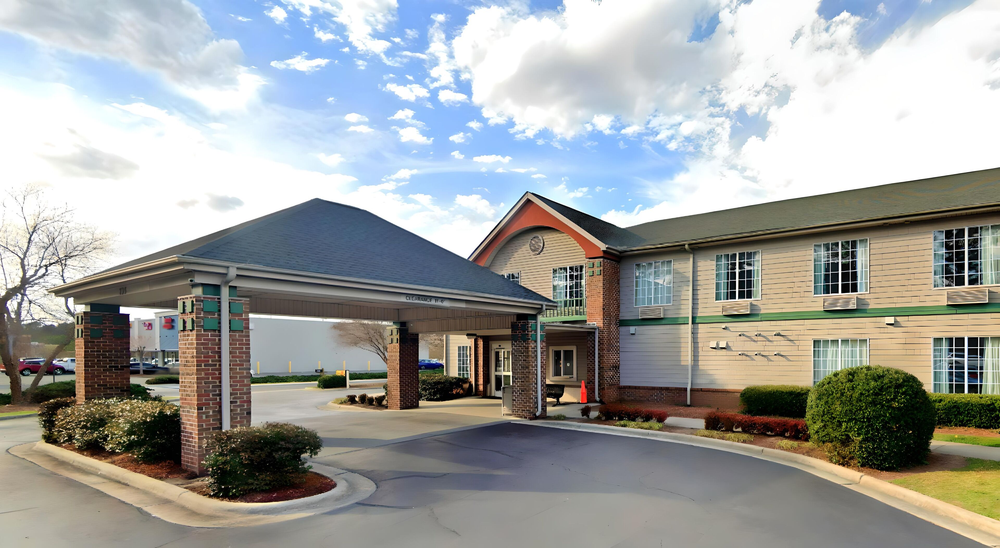 A hotel with a covered entrance, a brick facade, and a clear sky.