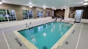 Una piscina interior con agua cristalina, con la inscripción 'NO DIVING' en el fondo, y ventanas que ofrecen vistas a coches aparcados afuera.
