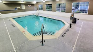 Una piscina interior con agua cristalina, marcas de profundidad y señalización de seguridad.