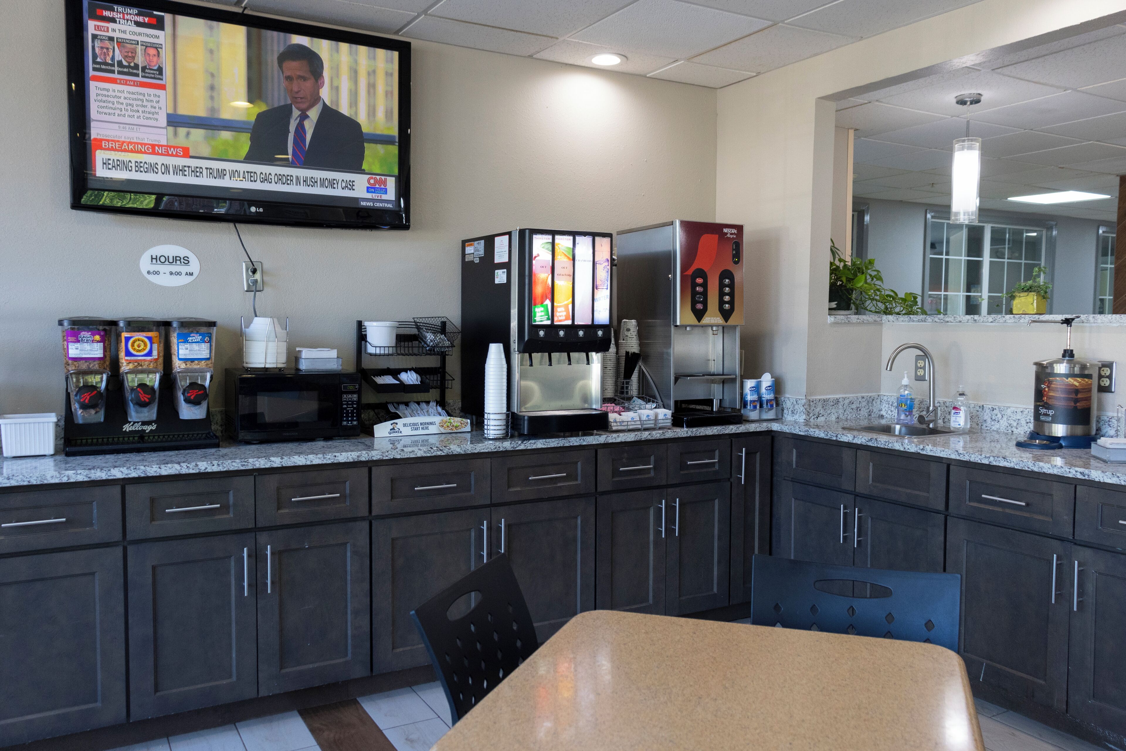 A modern kitchen with a coffee machine, microwave, and a TV displaying news.