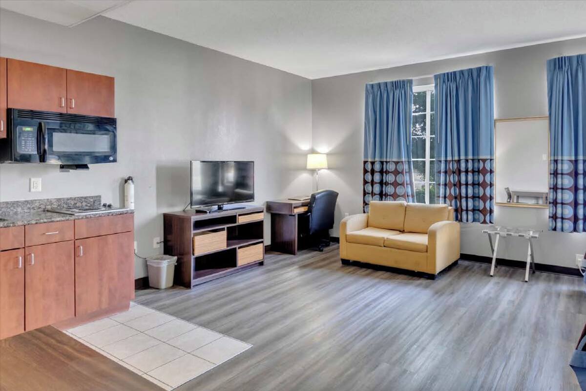 Una habitación de hotel con kitchenette, sofá, cama y televisor.