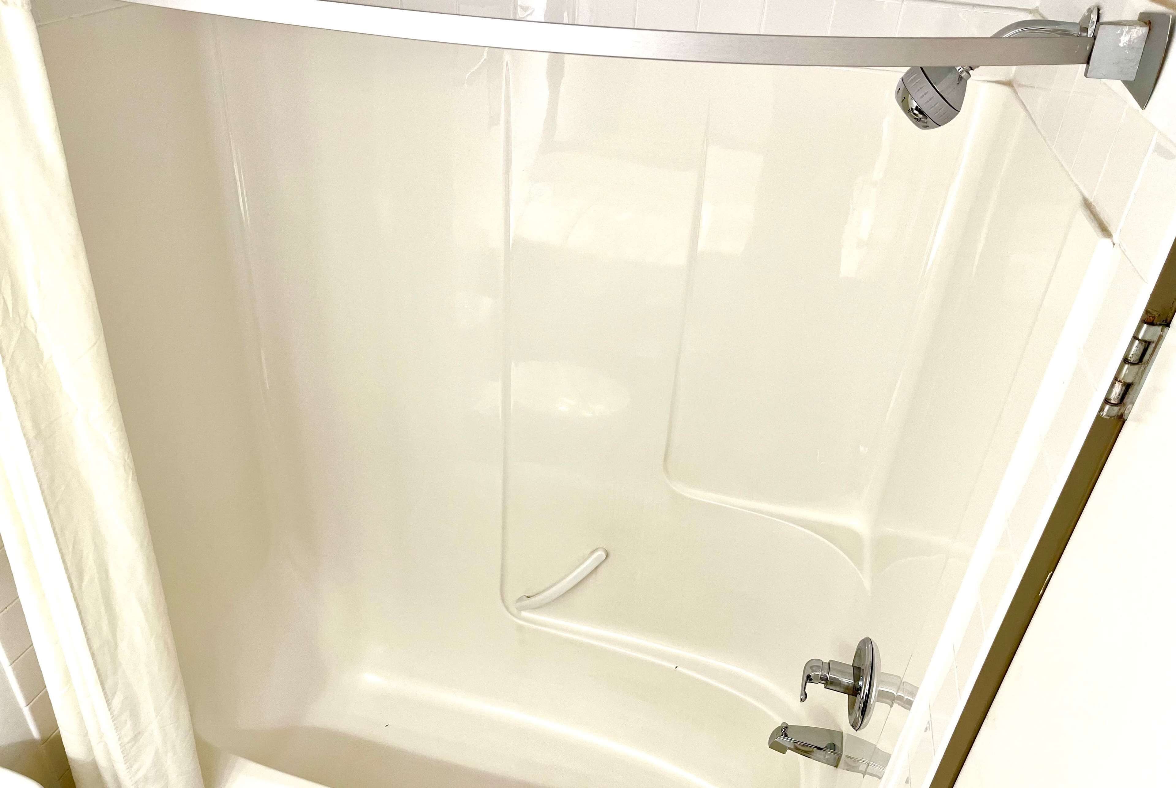 Eine weiße Badewanne mit Duschkopf und Wasserhahn.
