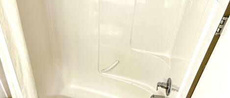 Eine weiße Badewanne mit Duschkopf und Wasserhahn.
