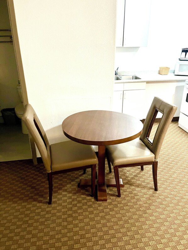Un comedor con una mesa redonda de madera y dos sillas tapizadas.