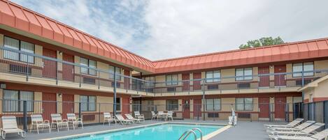 A hotel with a pool area, multiple balconies, and a red roof.