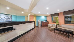 Un espace d’accueil avec un comptoir de réception en bois, un canapé, une table basse et, au fond, une petite kitchenette.