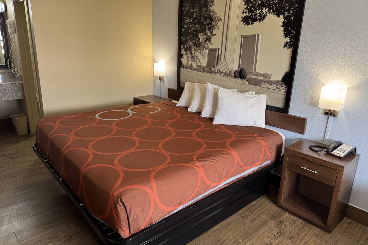Una camera d'albergo con un letto, lampade da comodino, un tavolino e uno specchio grande.